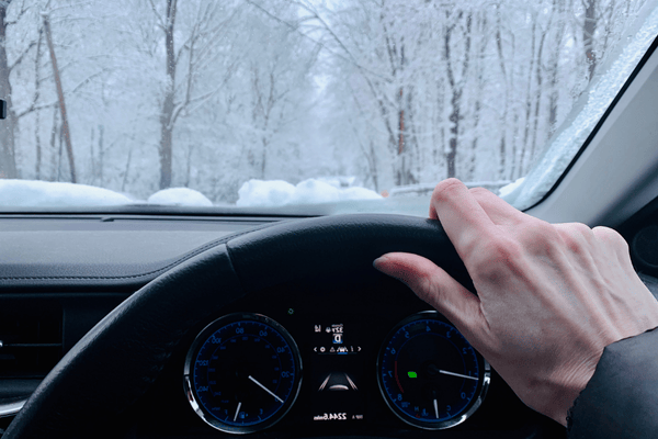 Dashboard and steering wheel of a car being driven in snow driving safety